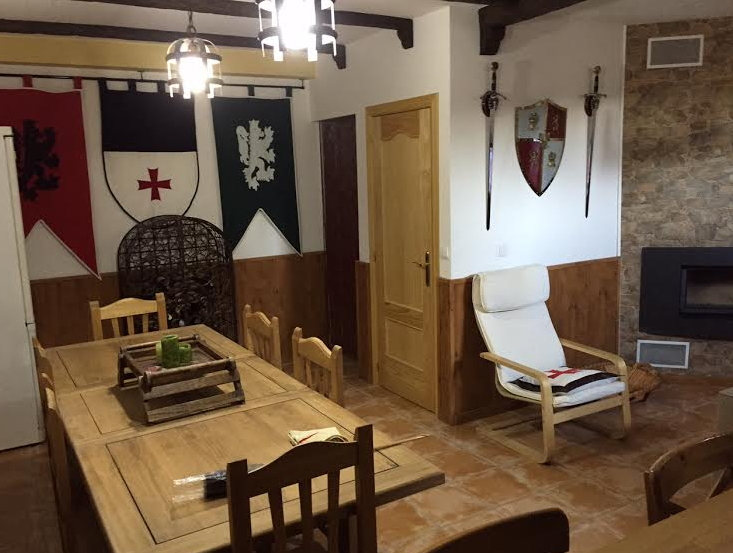 Decoración Medieval con estandartes, lámparas en forja, panoplia de escudo y espadas, mesa y sillas en madera